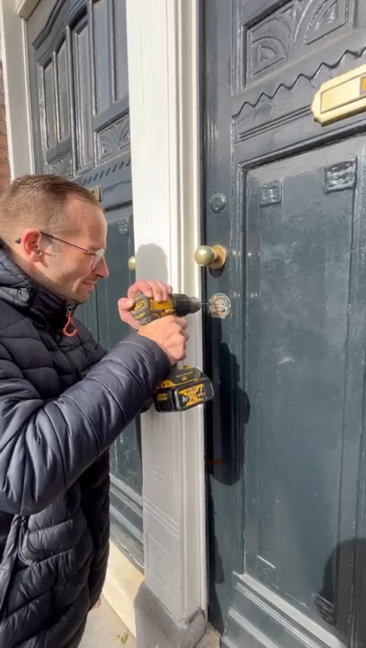 Slotenmaker boort aan een donkere voordeur